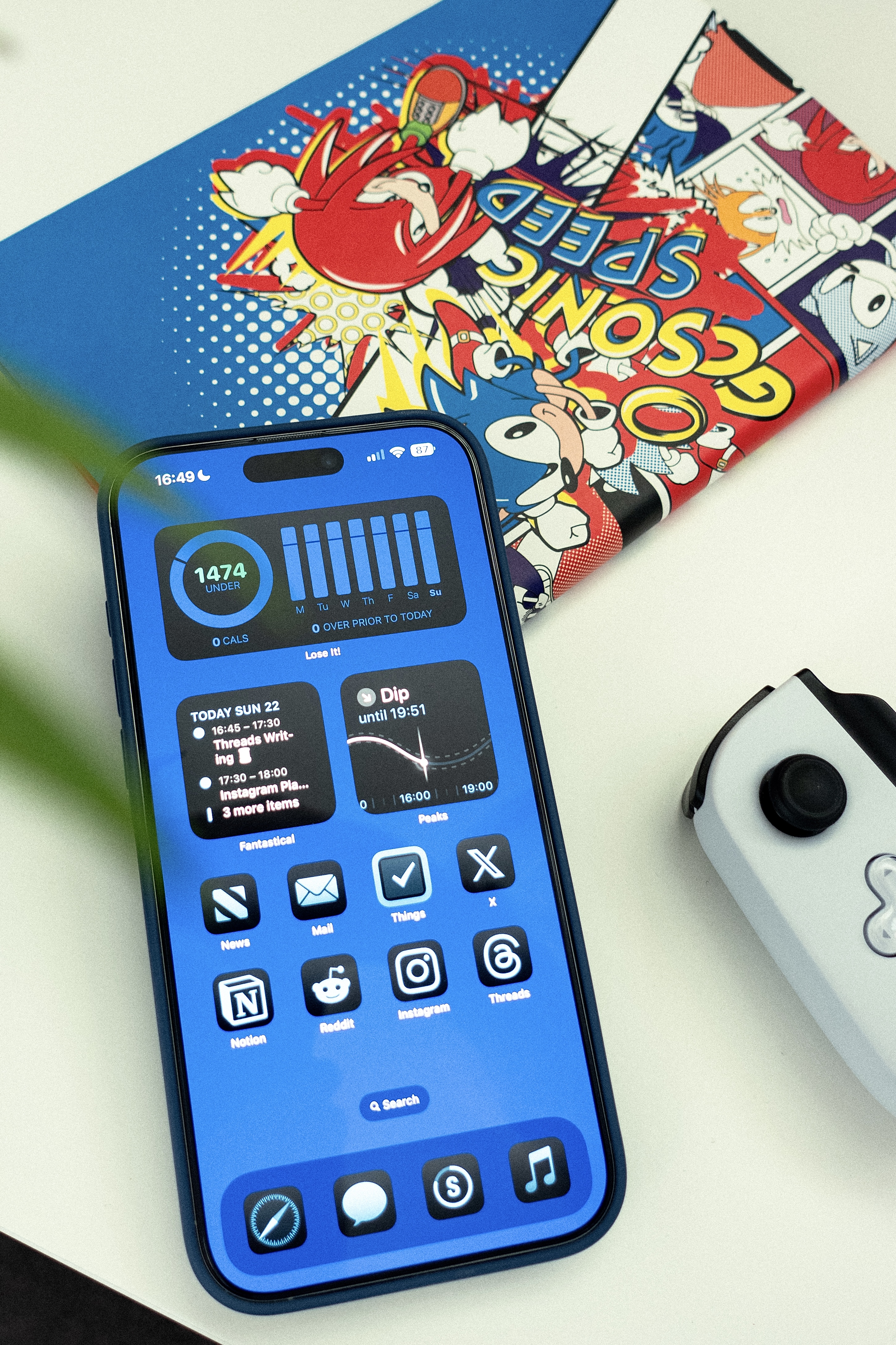 A top down view of the iPhone 16 Pro Max with various tech and gaming accessories.